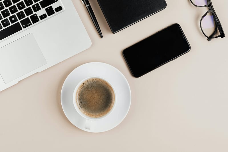 Rachel Jackson Marketing Tech Specialist a layout image of a desk with a cup of black coffee, a phone, a laptop and black glasses.