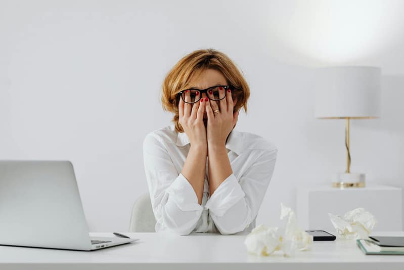 Rachel Jackson Marketing Tech Specialist. A minimalist white image of a woman with short hair and black glasses sat behind a desk which has a laptop on it, the woman has her head in her hands, obviously in tech distress and needs assistance from a marketing tech specialist :)