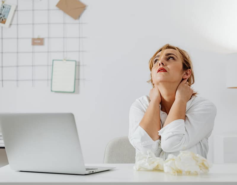 A white woman with blond hair sitting behind her laptop looking stressed.